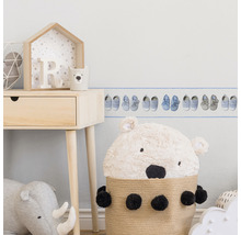 Szene eines Kinderzimmers mit einem Wandbordüren-Muster mit Babyschuhen, einem Holztisch und Stofftieren