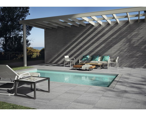 Terrasse mit Pool, Fliesenboden, Wandverkleidung und Sitzgruppe unter einer Pergola.