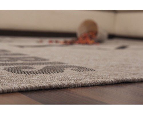 Detailansicht eines Teppichs mit Muster und einem umgefallenen Becher