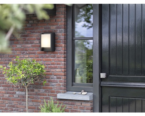 Außenwandleuchte an einer Ziegelmauer neben einer Haustür