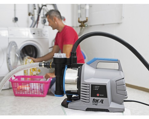 Hauswasserwerk im Einsatz im Waschkeller mit einer Person, die Wäsche in eine Waschmaschine legt