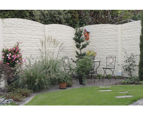 Gartenansicht mit dekorativem Betonsichtschutzzaun und Sitzgruppe