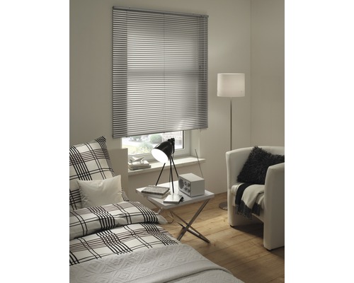Innenraum mit Fenster und installierter Jalousie, Bett, Sessel und Lampe