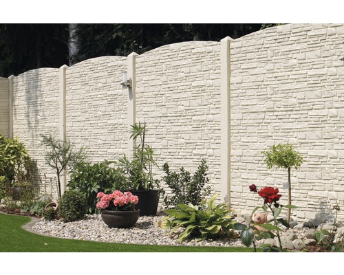 Betonzaun mit Pflanzen und Steinen im Garten