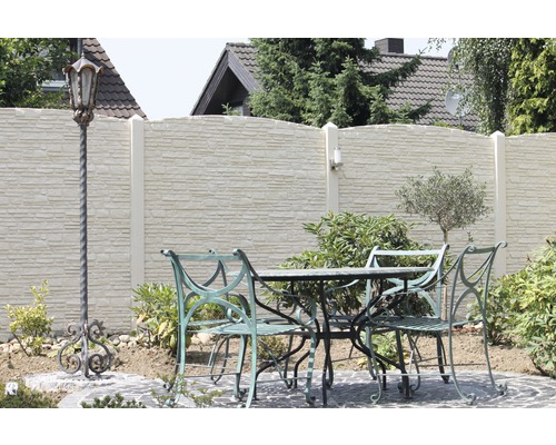 Gartenszene mit Steinmauer, Gartentisch, Gartenstühlen und einer dekorativen Laterne.