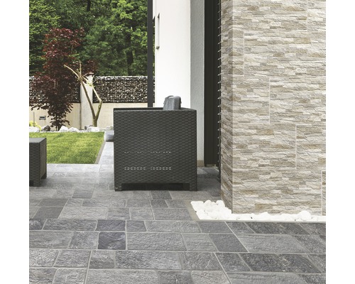 Terrasse mit grauen Steinplatten und einer Wand mit Verblendern in Steinoptik