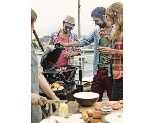 Personen grillen auf einem Dach mit einem Grill, Zutaten und Brötchen.