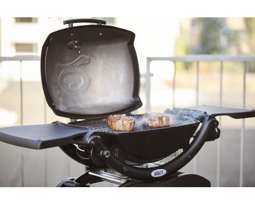 Offener Grill mit Grillgut und Weber Logo