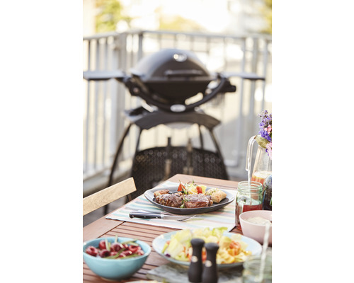Szene mit einem Grill, einem Tisch mit Speisen und Getränken auf einem Balkon.