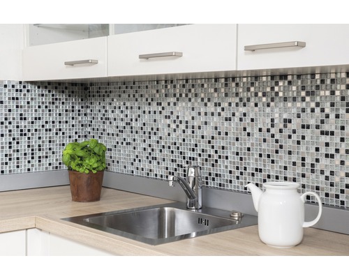 Küchenszene mit Mosaikfliesen, Spüle und Küchenutensilien auf einer Arbeitsplatte.