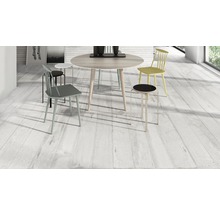 Heller Raum mit Esstisch und Stühlen auf Holzbodenoptikfliesen.