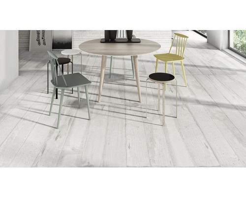 Heller Raum mit Esstisch und Stühlen auf Holzbodenoptikfliesen.