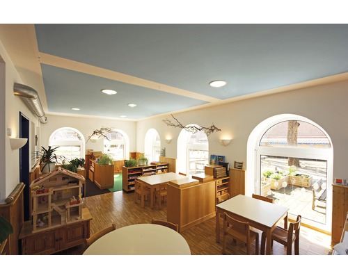 Helles Klassenzimmer mit Holzmöbeln und blauer Decke
