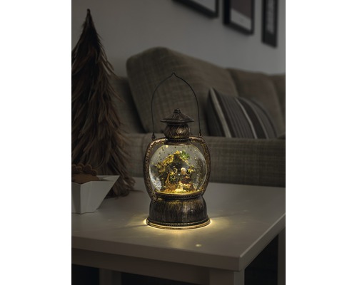 Dekorative Laterne mit Schneekugel und Weihnachtskrippe auf einem Tisch