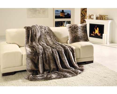 Dekorative Wohndecke und Kissen auf Sofa neben Kamin