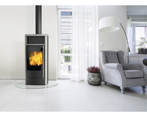 Wohnzimmer mit Kaminofen, Sessel und Zimmerpflanze