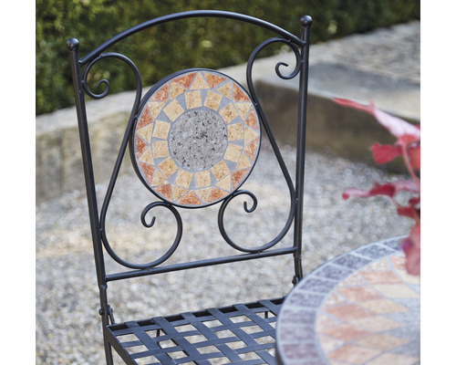 Detailansicht eines Gartenstuhls mit Mosaikmuster auf der Rückenlehne