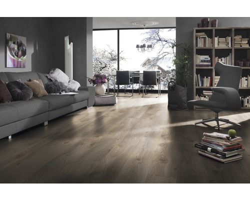 Wohnzimmer mit Sofa, Sessel, Bücherregal und Laminatboden.