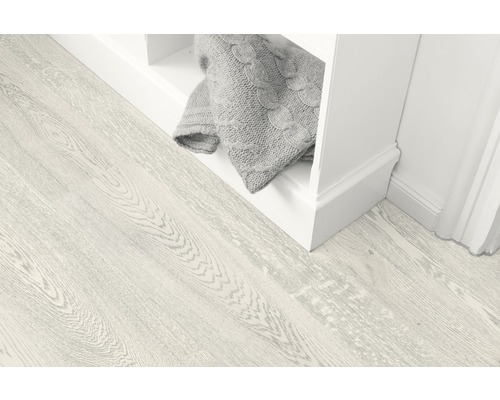 Heller Holzboden neben einem weißen Regal mit einer grauen Decke.