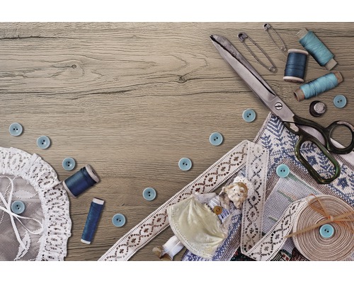 Nähszene mit Schere, Knöpfen, Garn, Sicherheitsnadeln, Spitze und Puppe auf einem Holztisch