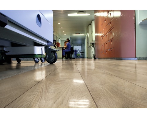 Heller Holzfußboden in einem Krankenhausflur mit medizinischen Geräten und Personal