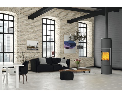 Wohnzimmer mit Kaminofen, Sofa und Esstisch in einem hellen Raum mit Backsteinwand