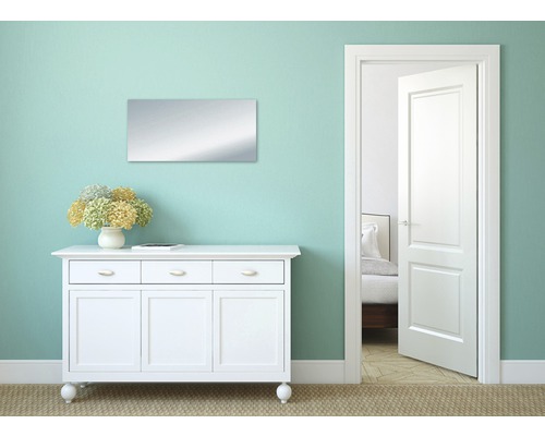 Interieuransicht mit rechteckigem Spiegel über einem weißen Sideboard, das mit Blumen dekoriert ist, und einer offenen Tür