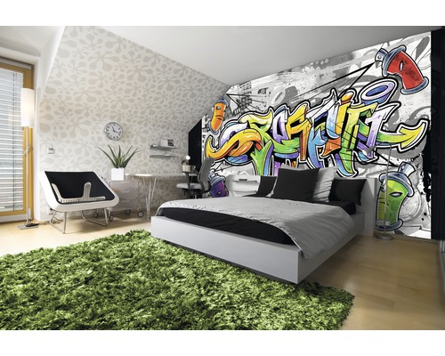 Modernes Schlafzimmer mit Graffiti-Fototapete, Bett, Schreibtisch und grünem Teppich.