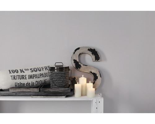 Dekoratives Stillleben mit Kissen, Dose, Kerzen und Buchstabe auf einem Regal