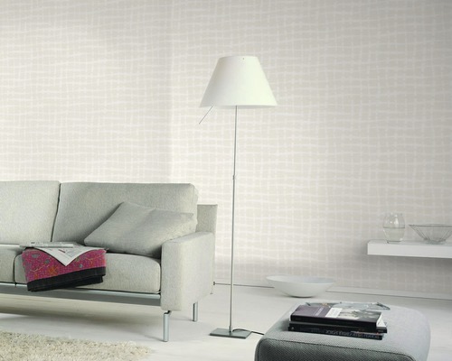 Wohnzimmer mit gemusterter Tapete, Sofa, Stehlampe und Ottomane für ein helles und organisiertes Ambiente.