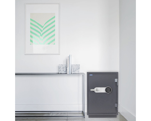 Grauer Tresor mit elektronischem Schloss in einem modern eingerichteten Raum.