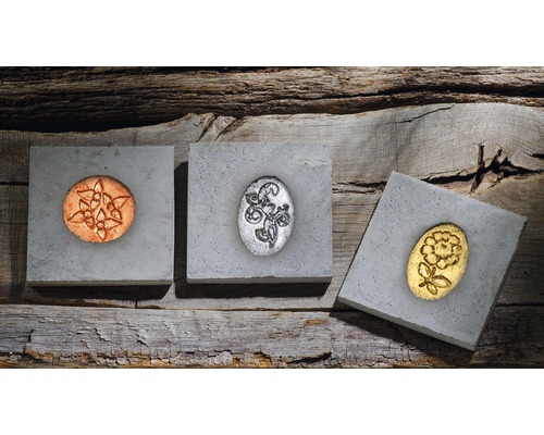 Drei Betonplatten mit Motiven auf Holzgrund