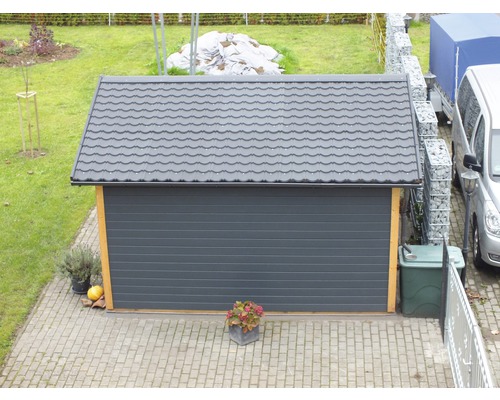 Garage mit grauem Rolltor und Ziegeldach im Garten
