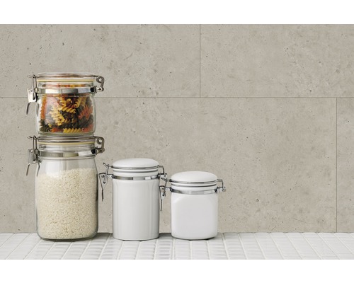 Vorratsgläser mit Pasta, Reis und weißen Behältern auf einer weißen Fliesenoberfläche vor einer grauen Wand