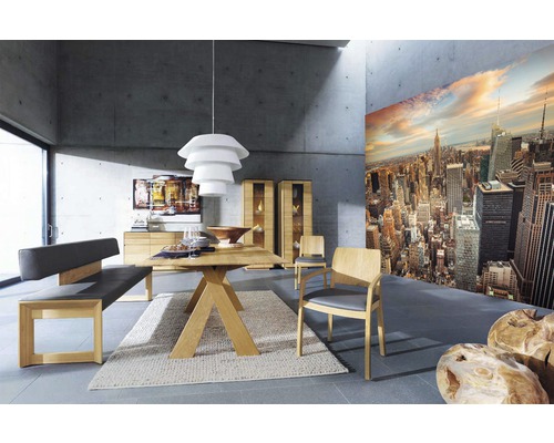 Helles Esszimmer mit Holztisch, Stühlen, Sitzbank, Anrichte, Vitrinen und einer New Yorker Skyline-Tapete.