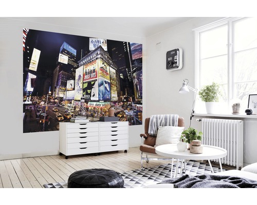 Wohnzimmer mit Fototapete einer nächtlichen Großstadtszene, Kommode und Sitzmöbeln.