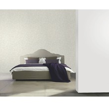 Schlafzimmer mit Bett, Kissen und Tapete an der Wand.