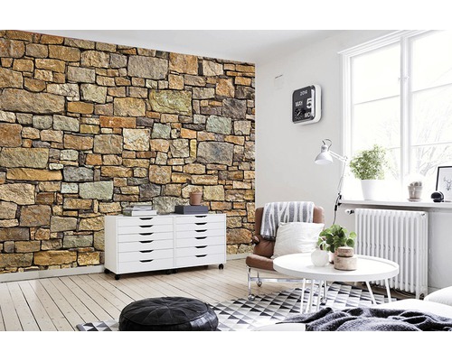 Wohnraum mit Steinwandtapete, Kommode, Sessel und Couchtisch.