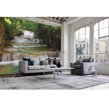 Wohnzimmer mit Fototapete eines Wasserfalls in einem Wald, hellem Sofa, Sessel und Teppich.