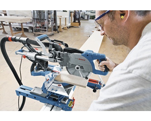 Eine Person bedient eine Bosch Kapp- und Gehrungssäge beim Sägen eines Werkstücks.
