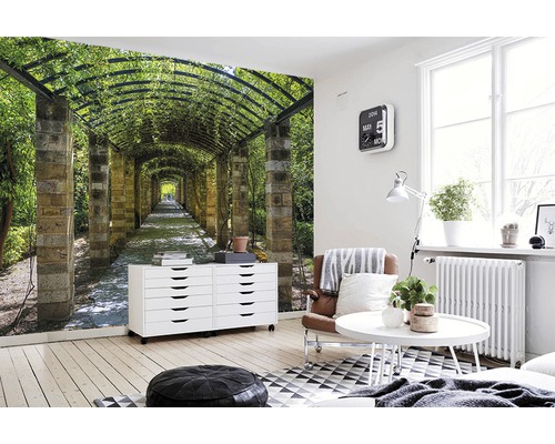 Wohnraum mit einer Fototapete mit dem Motiv eines Laubengangs.