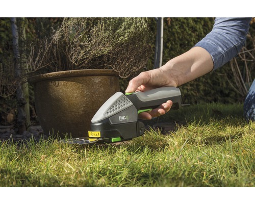 Eine Person benutzt eine Akku-Gras- und Strauchschere von for_q im Garten.