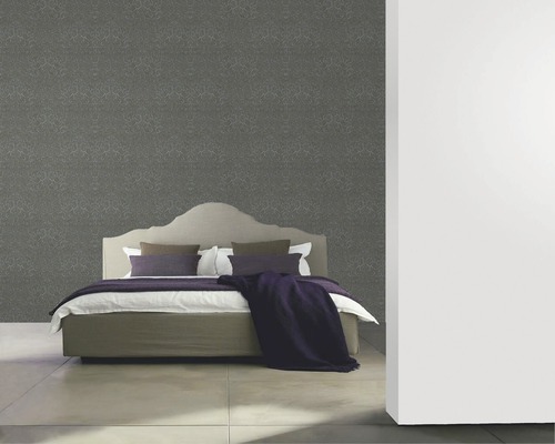 Schlafzimmer mit floral gemusterter Tapete hinter einem Bett