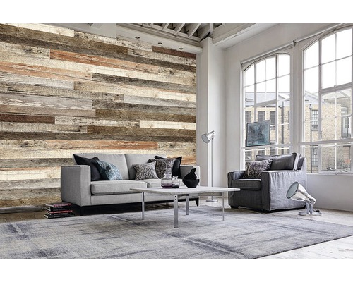 Wohnzimmer mit Wandpaneelen in Holzoptik, Sofa, Sessel und Teppich für eine gemütliche Atmosphäre.