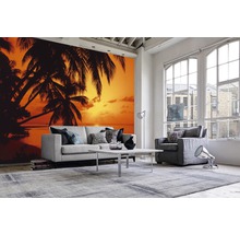 Wohnraum mit Fototapete mit Palmenmotiv und Sonnenuntergang am Strand, Sofa, Sessel, Teppich und Couchtisch