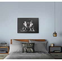 Schlafzimmer mit Bett, Nachttischen, Lampe und Wandbild mit Mickey Maus Motiv