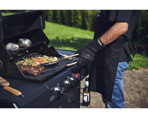 Grill mit Steak, Gemüse, Folienkartoffeln und Grillmeister mit Grillhandschuh.