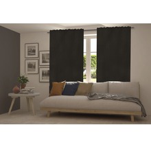 Wohnzimmer mit Sofa und blickdichten, schwarzen Gardinen vor dem Fenster.