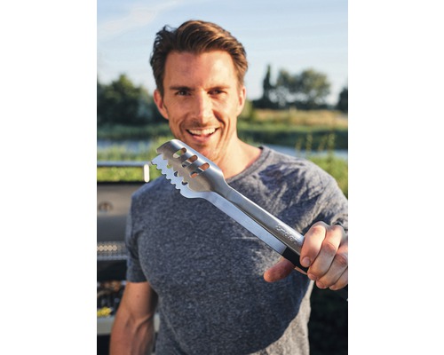 Eine Person hält eine Grillzange aus Metall in der Hand.