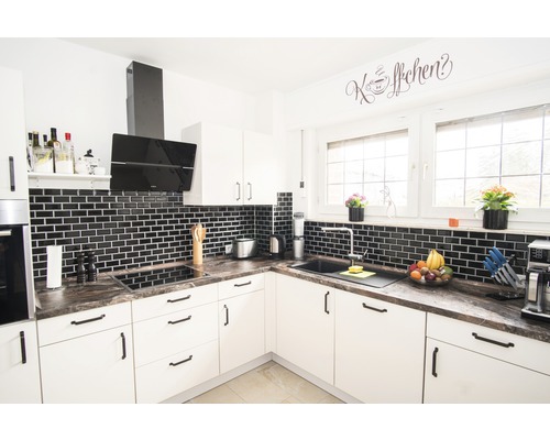 Helle Küche mit schwarzen Fliesen und moderner Ausstattung.